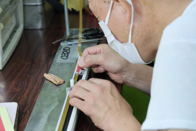 部品にテープを貼る細かい手作業